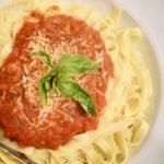 Easy homemade pasta sauce on gluten free pasta topped with basil and parmesan cheese