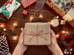 Gift Guide showing paper wrapped gift with red string and holiday lights